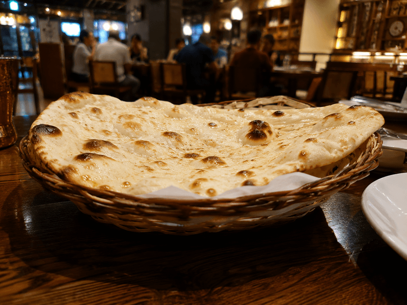 Naan photographed from eye level on a restaurant table with the background visible.